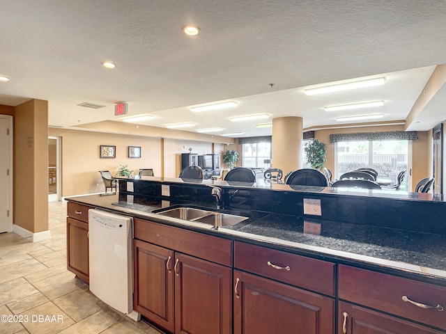 kitchen featuring a textured ceiling, sink, white dishwasher, and light tile patterned floors