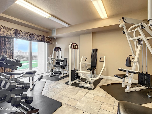 gym featuring a textured ceiling and light tile patterned floors