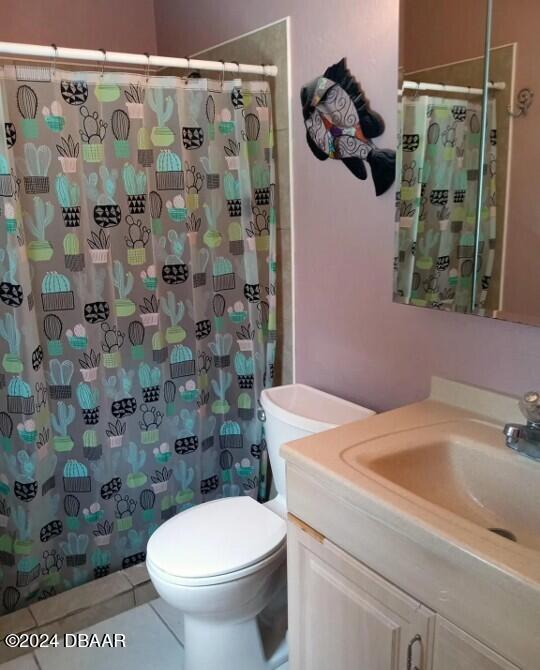 bathroom with tile patterned flooring, vanity, toilet, and walk in shower