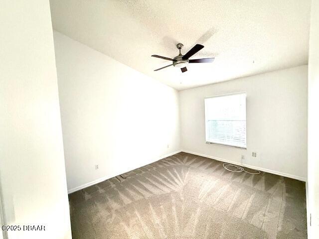 unfurnished room featuring ceiling fan, dark carpet, and a textured ceiling