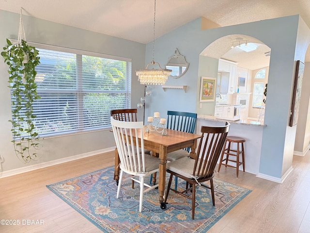 dining space with light wood-type flooring, lofted ceiling, and a chandelier