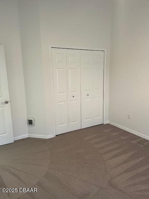 unfurnished bedroom with dark carpet and a closet