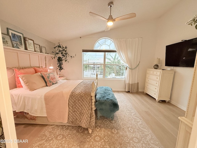 bedroom featuring a textured ceiling, ceiling fan, light hardwood / wood-style flooring, and vaulted ceiling