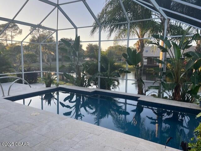 pool at dusk featuring glass enclosure and a patio area