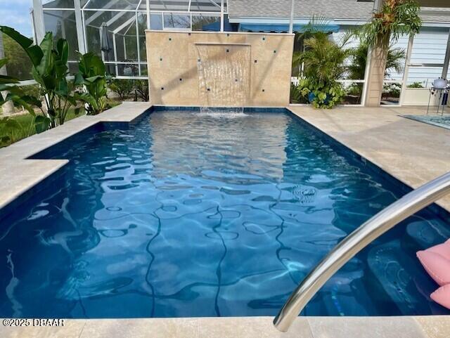 view of swimming pool featuring glass enclosure and a patio area