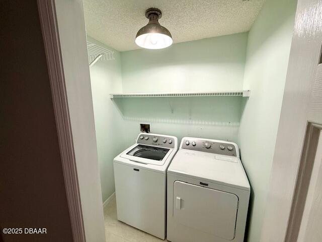 clothes washing area featuring washer and clothes dryer and light tile patterned floors