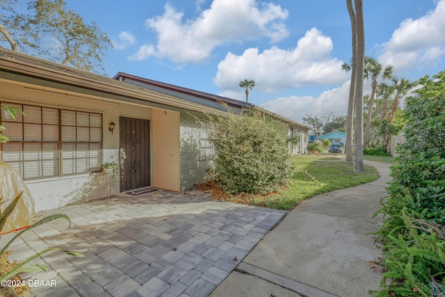 entrance to property with a patio and a lawn