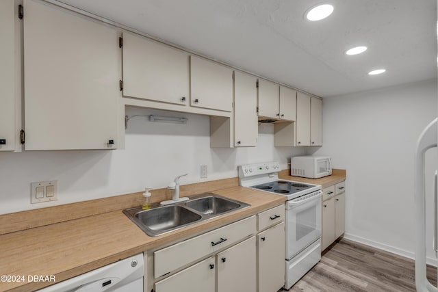 kitchen featuring white cabinets, light wood-type flooring, sink, and white appliances