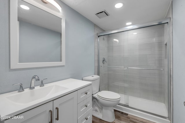 bathroom with wood-type flooring, vanity, toilet, and an enclosed shower