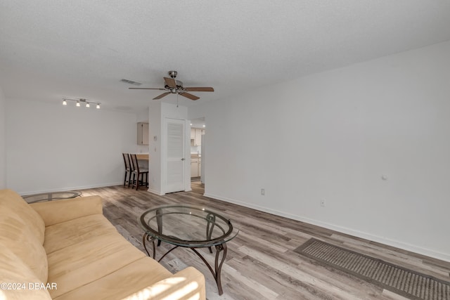 living room featuring hardwood / wood-style flooring, ceiling fan, and a textured ceiling