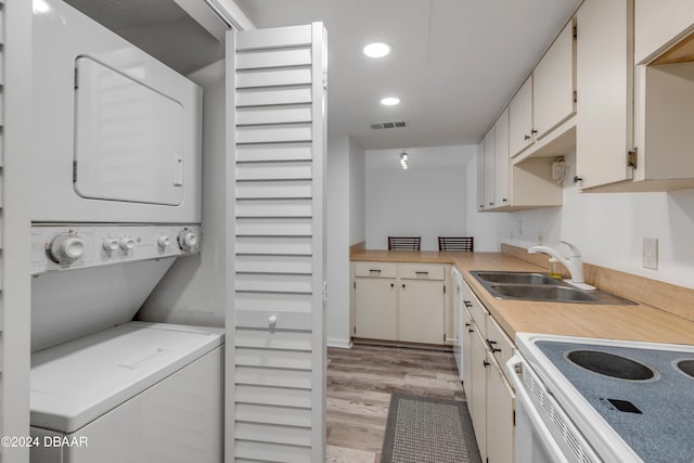 kitchen featuring stacked washer / dryer, light wood-type flooring, and sink