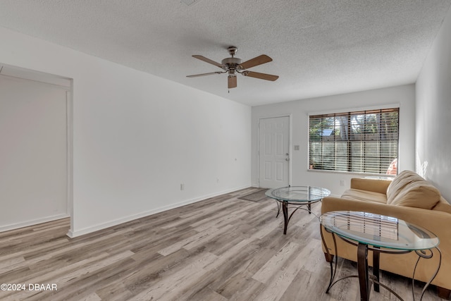 living room featuring a textured ceiling, light wood-type flooring, and ceiling fan