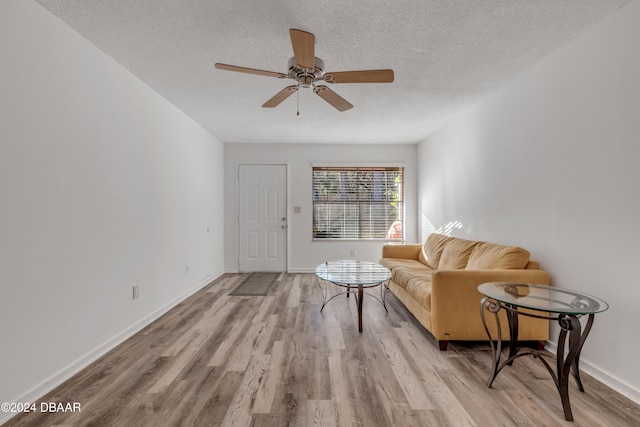 living room featuring ceiling fan, a textured ceiling, and light hardwood / wood-style flooring