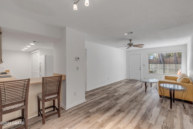 living area with a textured ceiling, hardwood / wood-style flooring, and ceiling fan