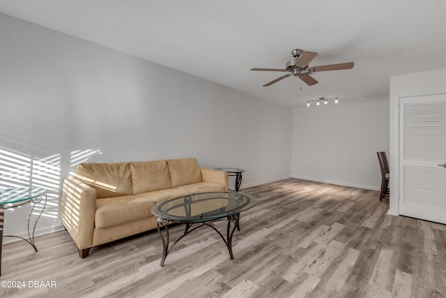 living room with ceiling fan, a textured ceiling, and light hardwood / wood-style flooring