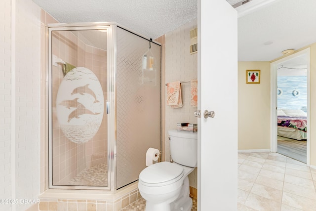 full bathroom featuring tile patterned floors, toilet, a stall shower, a textured ceiling, and ensuite bath