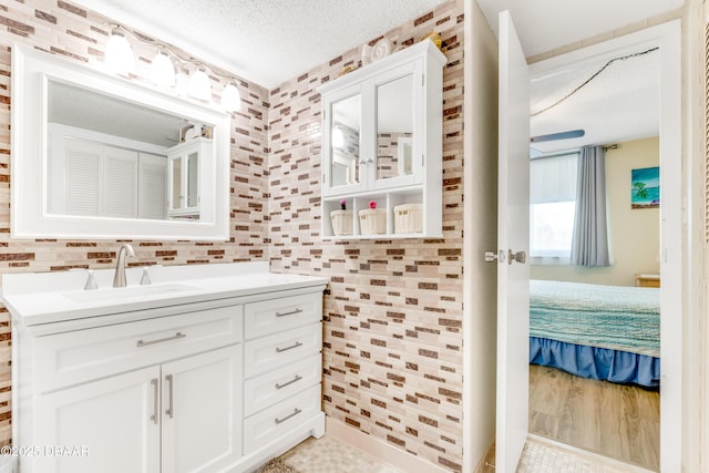 ensuite bathroom with connected bathroom, a textured ceiling, and vanity