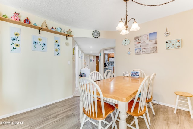 dining room with an inviting chandelier, baseboards, light wood-type flooring, and a textured ceiling