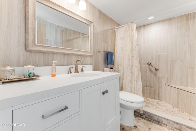 full bathroom with a tile shower, toilet, and vanity