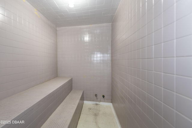 bathroom with tile patterned flooring, tile walls, and a tile shower