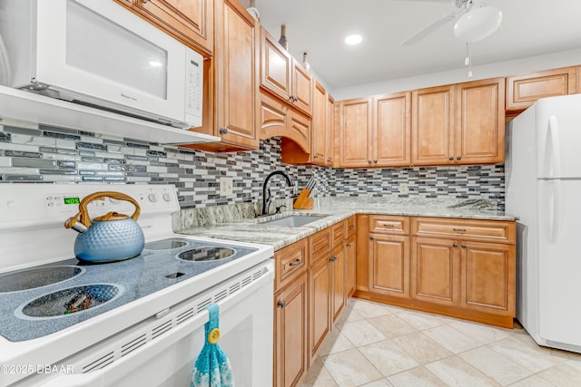 kitchen featuring a sink, light stone counters, tasteful backsplash, white appliances, and light tile patterned flooring