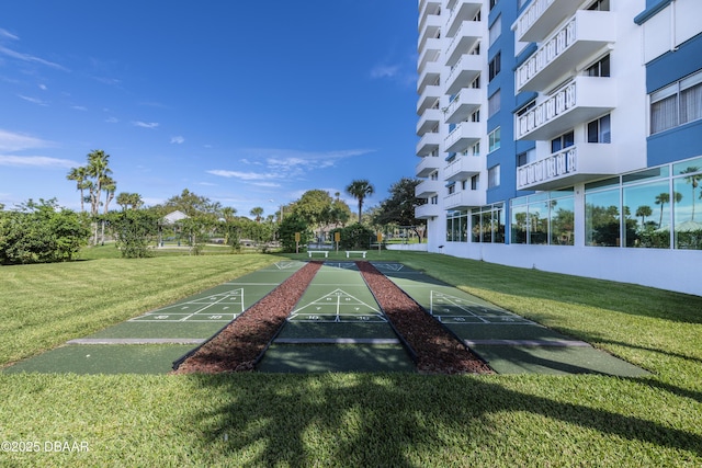 view of home's community with shuffleboard and a lawn