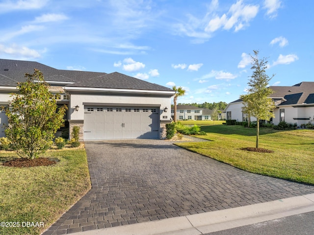 view of front of property with a garage, stone siding, decorative driveway, a front lawn, and stucco siding