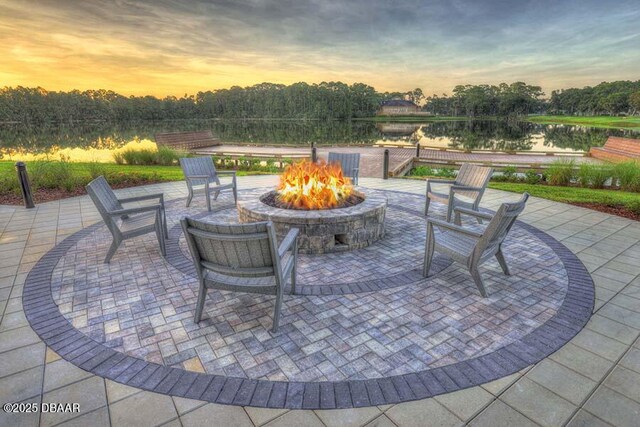 patio terrace at dusk featuring a water view and a fire pit