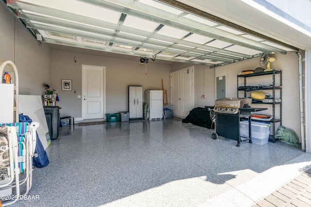 garage with a garage door opener, freestanding refrigerator, and electric panel