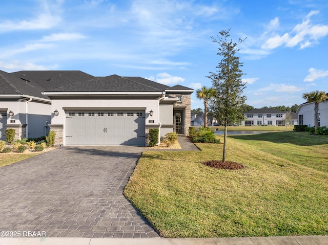 view of front of home with a front lawn, decorative driveway, an attached garage, and stucco siding