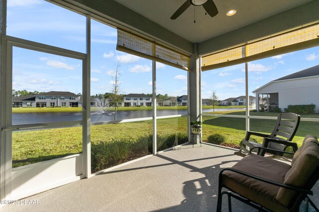 sunroom / solarium with a water view, a residential view, and a ceiling fan