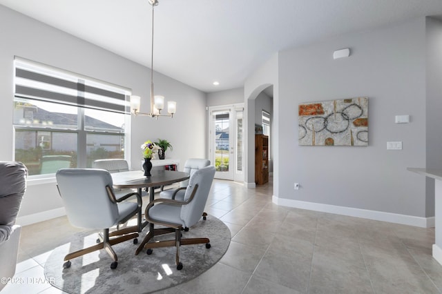 dining area featuring arched walkways, light tile patterned floors, a notable chandelier, and baseboards