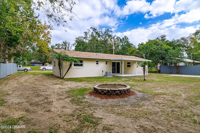 back of property featuring central AC, a fire pit, and a patio area