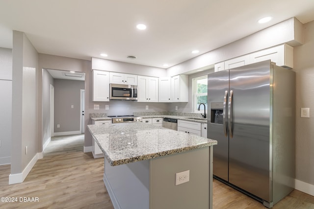 kitchen featuring white cabinets, light hardwood / wood-style flooring, sink, a kitchen island, and appliances with stainless steel finishes