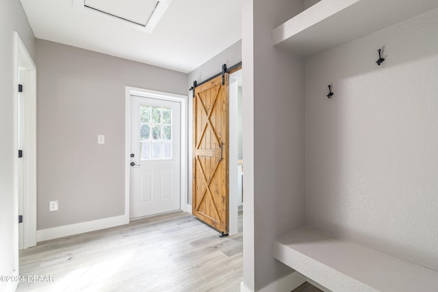 mudroom with a barn door and light hardwood / wood-style floors