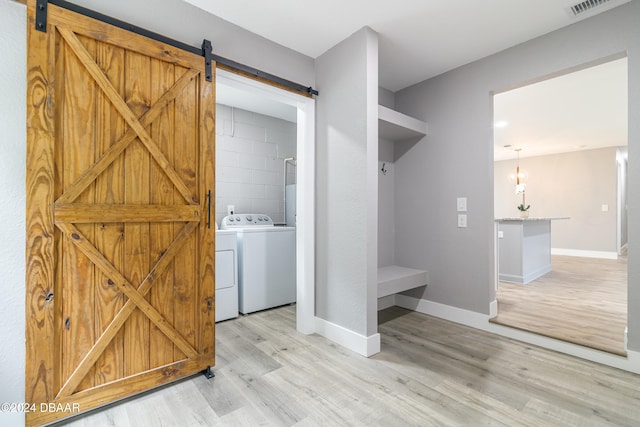 washroom featuring a barn door, light hardwood / wood-style floors, and washing machine and dryer