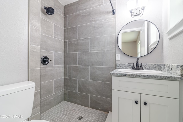 bathroom with toilet, vanity, and a tile shower