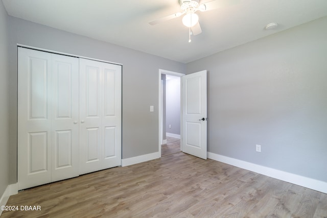 unfurnished bedroom with light wood-type flooring, ceiling fan, and a closet