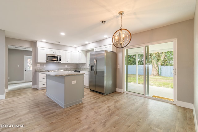 kitchen featuring a center island, light stone counters, hanging light fixtures, white cabinetry, and appliances with stainless steel finishes