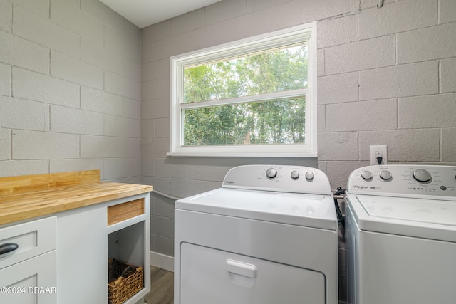 laundry room with washing machine and clothes dryer, wood-type flooring, and cabinets