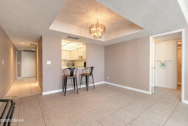 3047 S Atlantic Ave Unit 706, Daytona Beach Shores, FL 32118 - dining room featuring a textured ceiling, light tile patterned floors, a chandelier, and a raised ceiling