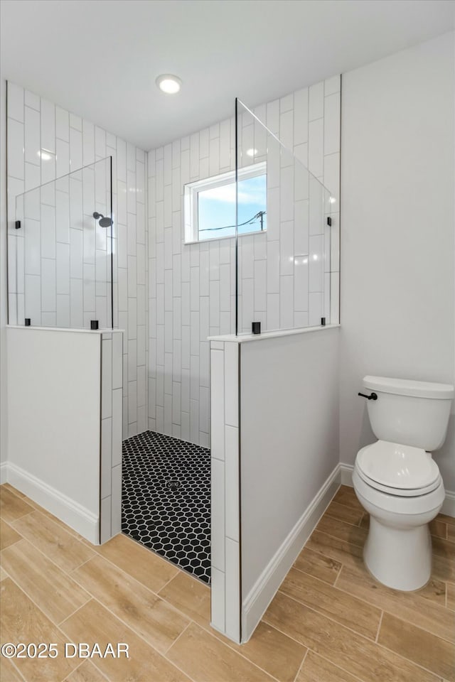 bathroom with a tile shower and toilet