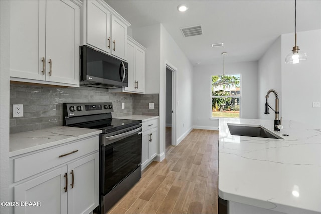 kitchen with light stone countertops, black range with electric cooktop, sink, decorative light fixtures, and white cabinetry