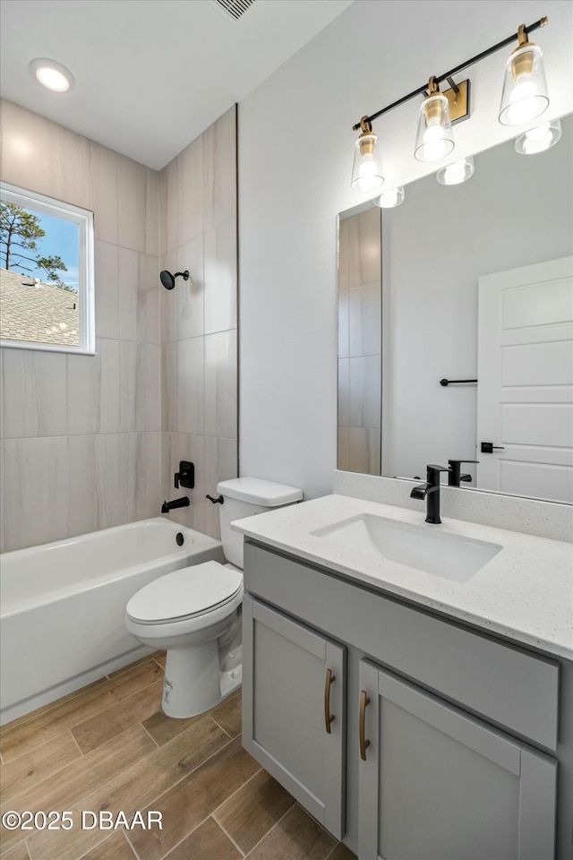 full bathroom featuring vanity, tiled shower / bath combo, and toilet