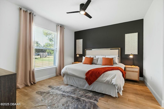 bedroom with ceiling fan, multiple windows, and light hardwood / wood-style flooring