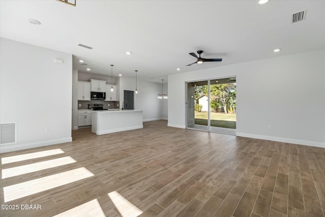 unfurnished living room featuring ceiling fan, sink, and wood-type flooring