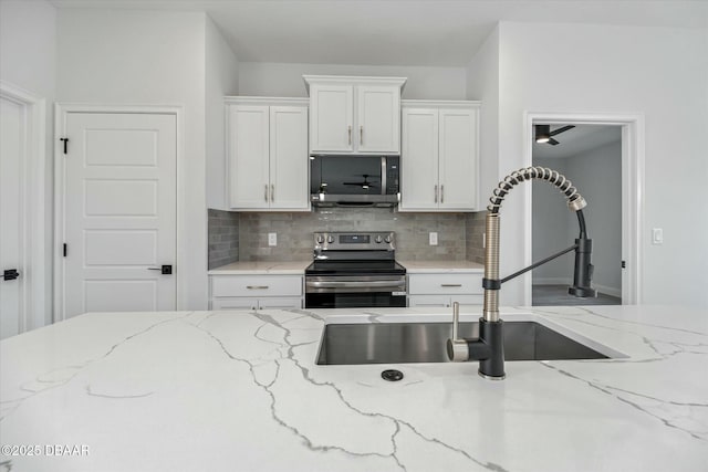 kitchen featuring backsplash, white cabinets, sink, light stone countertops, and appliances with stainless steel finishes