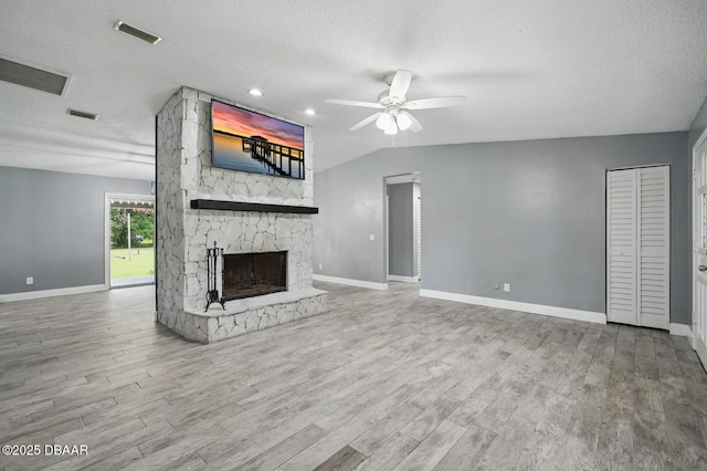 2950 Ragis Rd, Edgewater, FL 32132 - unfurnished living room with a ceiling fan, wood finished floors, a stone fireplace, and a textured ceiling
