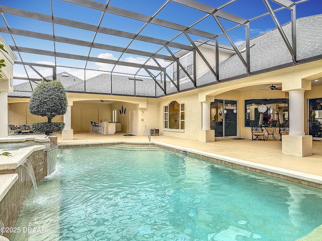 view of swimming pool with pool water feature, a patio area, ceiling fan, and glass enclosure