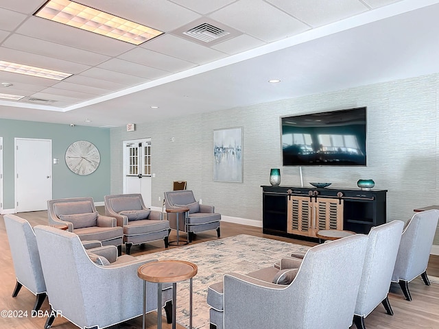 living room featuring a drop ceiling and light hardwood / wood-style floors